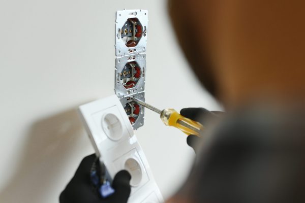 Electrician installs decorative frame on electric and TV sockets.