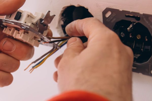 repair, renovation, electricity and electrician hands with screwdriver fixing socket