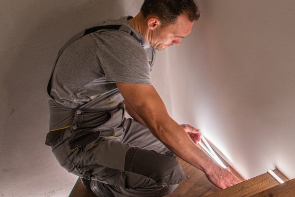 Stairs and Railing Contractor Finishing Wooden Residential Stairs with LED Lighting Illumination. Home Improvement Theme.